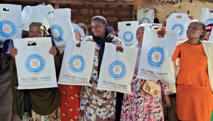 Families holding Helping Hand for Relief and Development Qurbani meat packs